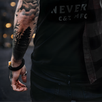 Man with black shirt with visible tattoos on arm and hand wearing luxury black paracord bracelet with gold shackle